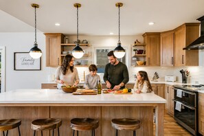 A modern kitchen with wooden cabinets, a central island, and pendant lighting.