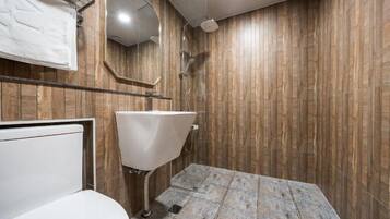 Een badkamer met een houten wand, een witte wastafel en een douche.