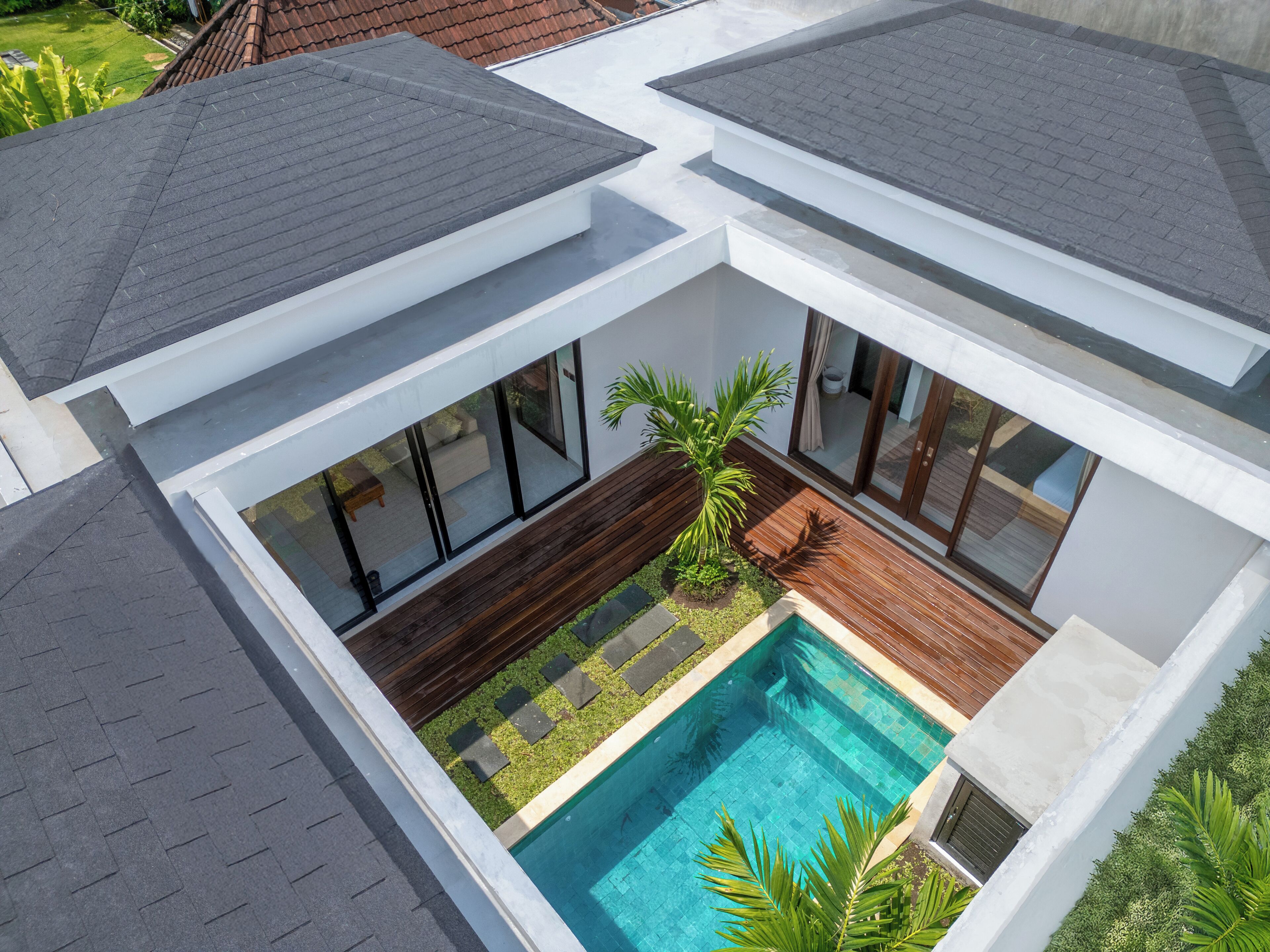 A modern house with a swimming pool, wooden deck, and large windows.