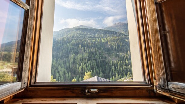 A window with a view of a forested mountain range.