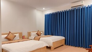 A hotel room with two wooden beds, white bedding, a blue curtain, and a wooden chair. - Huong Que Hotel HN - by BAY LUXURY (Hanoi)