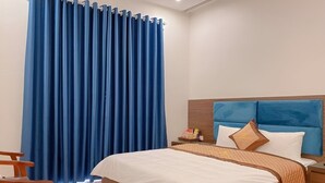 A hotel room with a large bed, wooden headboard, and a blue curtain. - Huong Que Hotel HN - by BAY LUXURY (Hanoi)