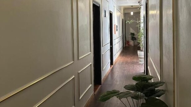 A long, narrow hallway with white walls and wooden flooring. There are doors on the left side, and a hanging light fixture in the center. - Huong Que Hotel HN - by BAY LUXURY (Hanoi)
