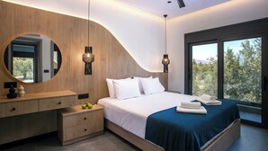 Un dormitorio moderno con techo curvo, una cama grande con ropa de cama blanca, un aparador de madera y un amplio ventanal con vistas a árboles.