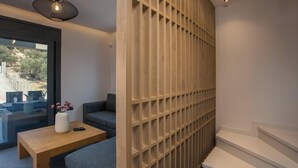 Un interior moderno con un separador de madera, un sofá, una mesa de centro y vistas a través de un ventanal.