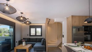 Cocina moderna con refrigerador, microondas y horno integrados. Cuenta con comedor con mesa y sillas, y un sofá en la sala.