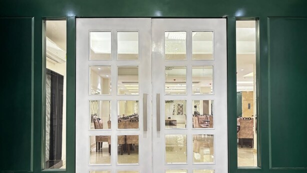 Puertas dobles con varios paneles de vidrio que dan a un espacio con comedor visible a través del vidrio.