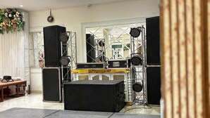 Un escenario con equipo de sonido, una mesa de madera y una decoración floral.