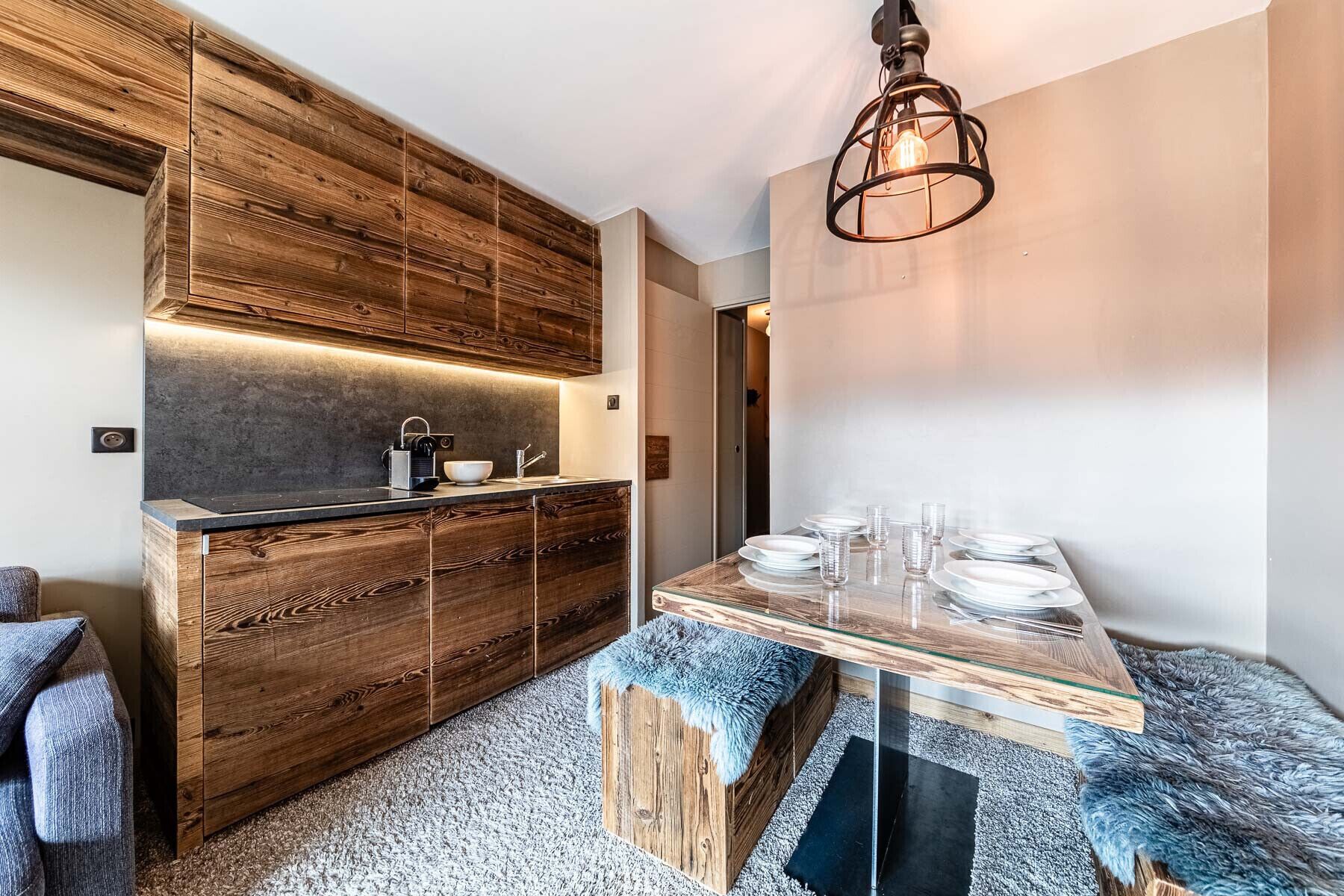 A modern kitchen with wooden cabinetry, a built-in stove, and a dining area with a glass table and chairs.