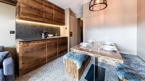 Eine moderne Küche mit Holzschränken, einem eingebauten Herd und einem Essbereich mit einem Glastisch und Stühlen.