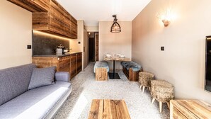 Ein kompakter Wohnbereich mit Küchenzeile, Essplatz und einer Sitzecke mit Sofa und Poufs.