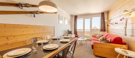Un comedor con una mesa de madera, sillas y una lámpara colgante.