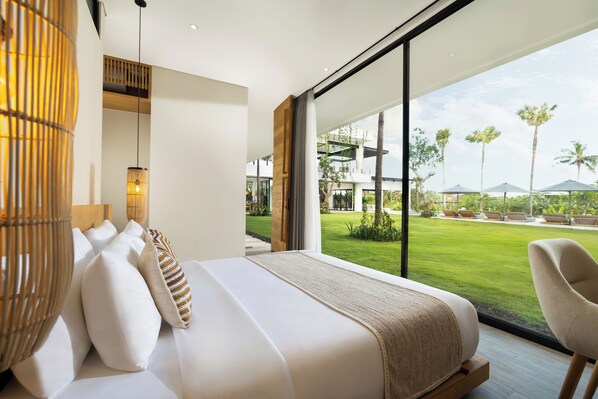 A modern bedroom with a large bed, a view of a well-maintained lawn and palm trees, and a large window. - Arita Villa Canggu by Nakula (Canggu)