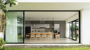 Une cuisine moderne dotée d’un grand îlot central, d’appareils électroménagers intégrés et d’une porte-fenêtre coulissante donnant sur un patio.