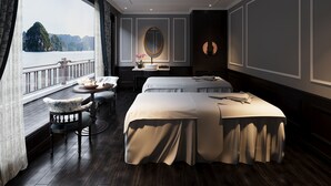 Ein Hotelzimmer mit großem Fenster, rundem Spiegel, Bett, Schreibtisch und Stuhl.