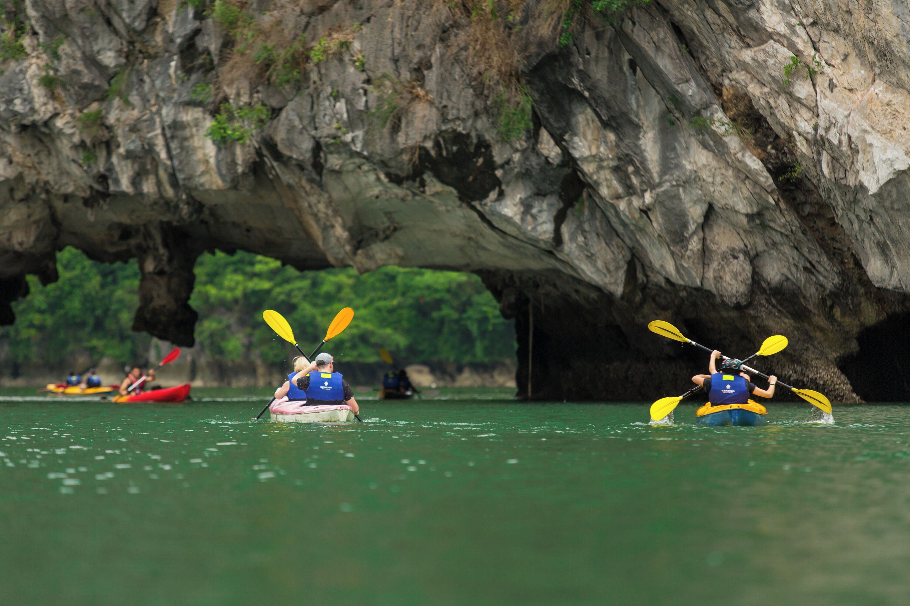 Kayakers in a calm river with a large rock formation in the background.