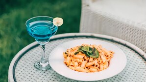 En tallerken med pasta og pynt på et rundt bord med flettet kant.