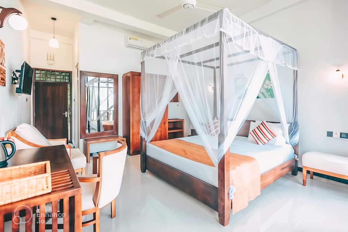 A modern bedroom with a four-poster bed, a desk, and a chair.