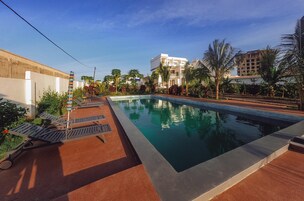 Una piscina al aire libre, sombrillas, sillones reclinables de piscina