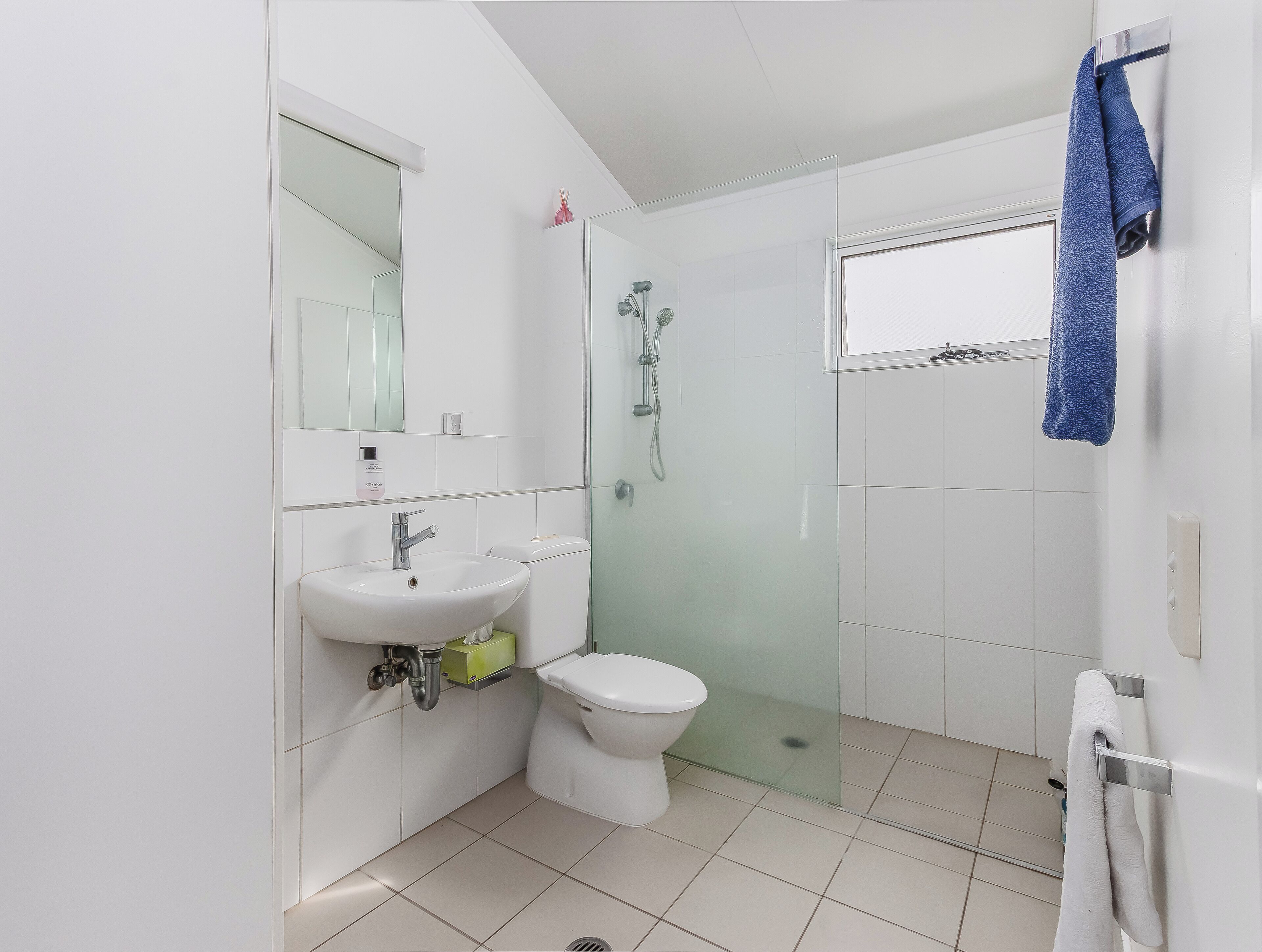 Une salle de bain moderne avec un lavabo, des toilettes et une douche, le tout de couleur blanche.