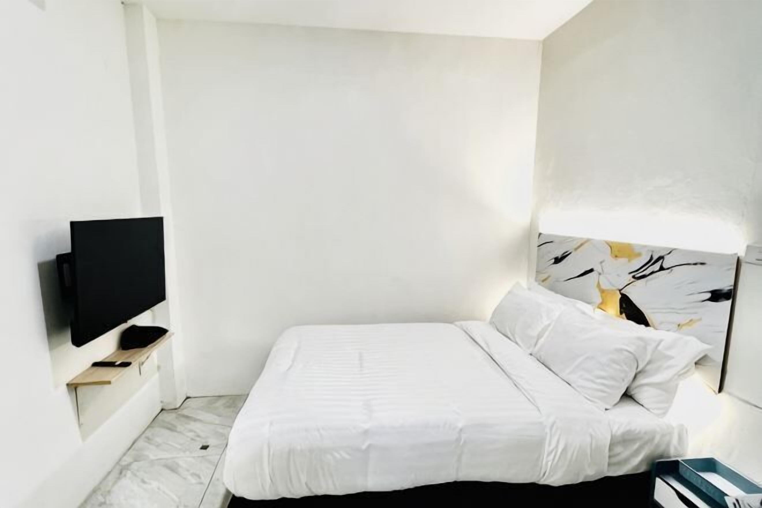 A bedroom with a bed, a TV, and a wall-mounted artwork.