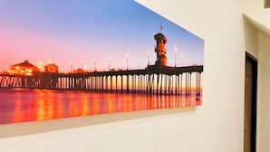 Una pared con un cuadro de un muelle al atardecer.