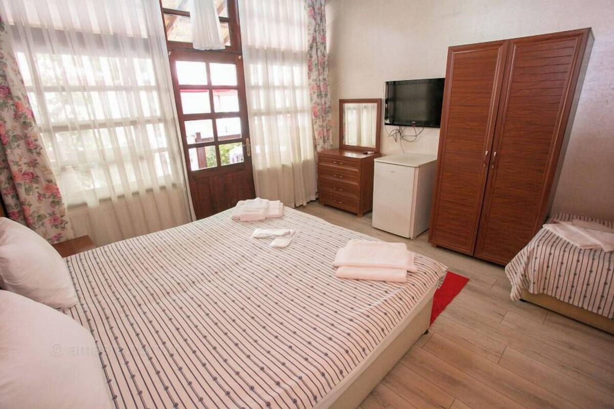 Un dormitorio con cama, cómoda, televisor y armario.