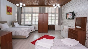 A hotel room with two beds, a wardrobe, a desk, and a television. - çarşı pansiyon (Amasra)