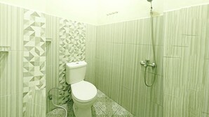 A bathroom with a toilet, shower, and patterned walls. - Pudan Residence Balige By Helocus (Balige)