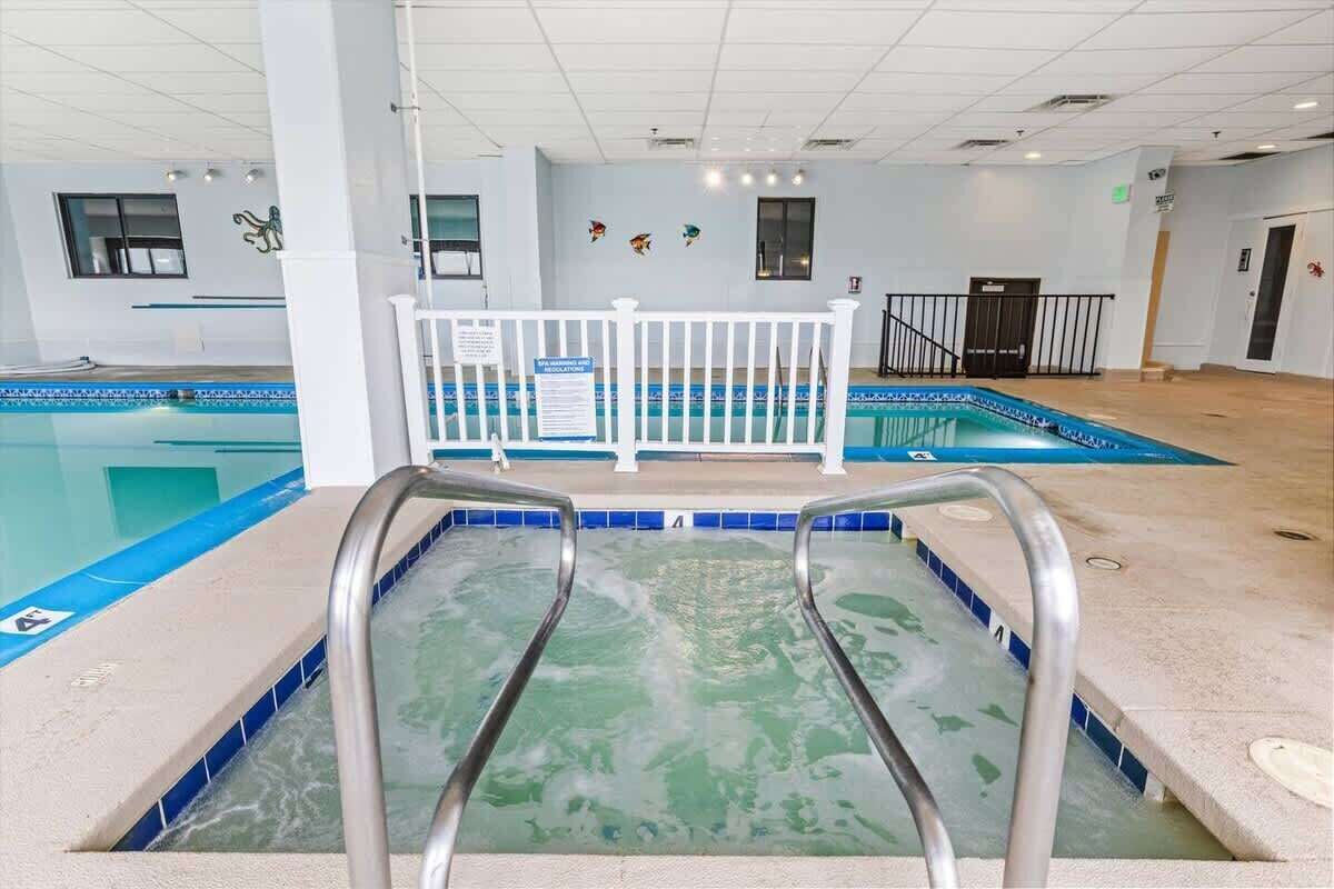 Una piscina interna con recinzione bianca, acqua cristallina e pavimento piastrellato.