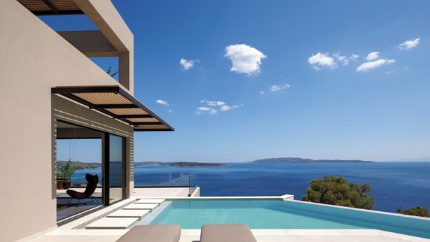 A modern outdoor pool area with a clear view of the sea and distant land. - Villa Apollo Porto Cheli (Ermionida)