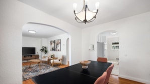 Un comedor con una mesa negra, sillas de madera y un candelabro.