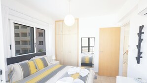 Ein modernes Hotelzimmer mit einem großen Bett, einem Kleiderschrank, einem Badezimmer und Blick ins Freie.