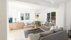 Ein modernes Wohnzimmer mit einer Sofagarnitur, einem Couchtisch und einem Fernseher.