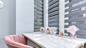Une salle de bain moderne avec un meuble-lavabo en marbre, une chaise rose et des objets décoratifs.