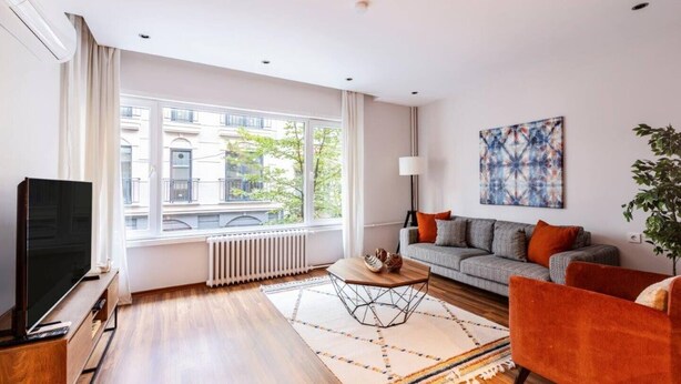 Un salon moderne avec une grande fenêtre, un téléviseur à écran plat, un canapé et une table basse.