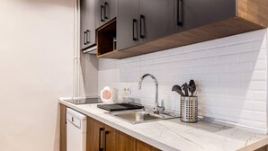 Une cuisine moderne dotée d’un plan de travail en marbre blanc, d’un évier en acier inoxydable et de meubles en bois.