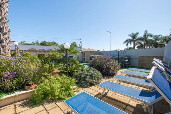 Un espace piscine aménagé sur le toit, avec des chaises longues, une échelle et diverses plantes.