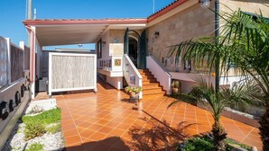 Une maison avec un patio carrelé, un escalier et une entrée abritée.