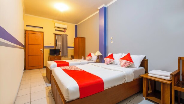 Une chambre d’hôtel avec un grand lit, une armoire en bois, une télévision et une salle de bain équipée d’une douche et de toilettes.
