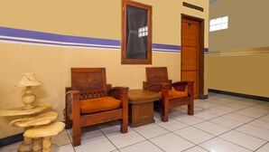 Une chambre d’hôtel avec deux chaises en bois, une petite table et une lampe.