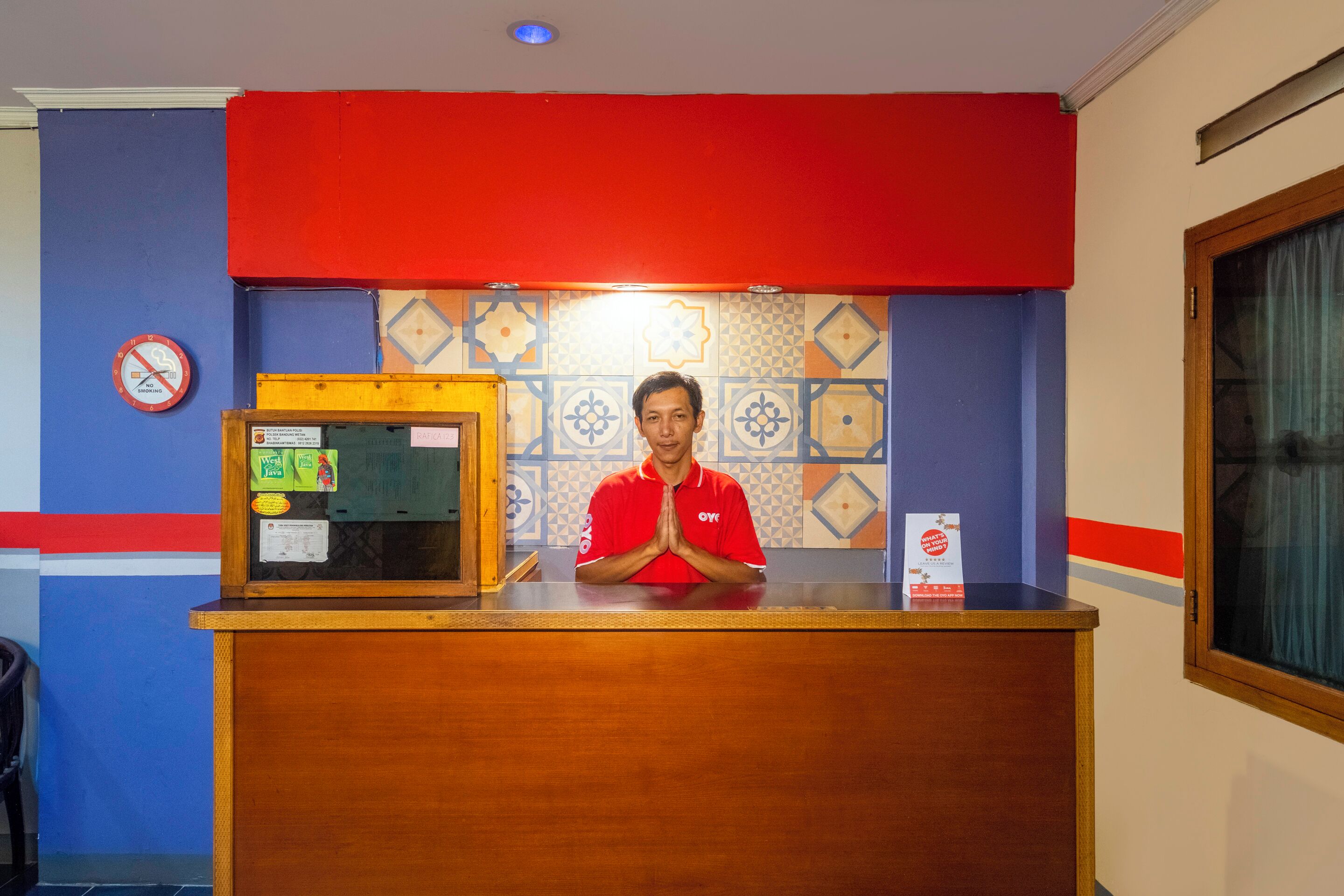 A hotel reception desk with a person in a red uniform standing behind it.