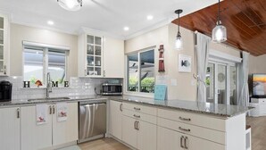 A modern kitchen with white cabinetry, stainless steel appliances, and a wooden ceiling. - 3BR Marco Island home with heated pool, WiFi and full kitchen. (Marco Island)