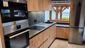 Eine moderne Küche mit Edelstahlgeräten, Holzschränken und einem großen Fenster.