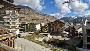 Un pueblo de montaña con edificios de madera, cielo despejado y montañas nevadas al fondo.