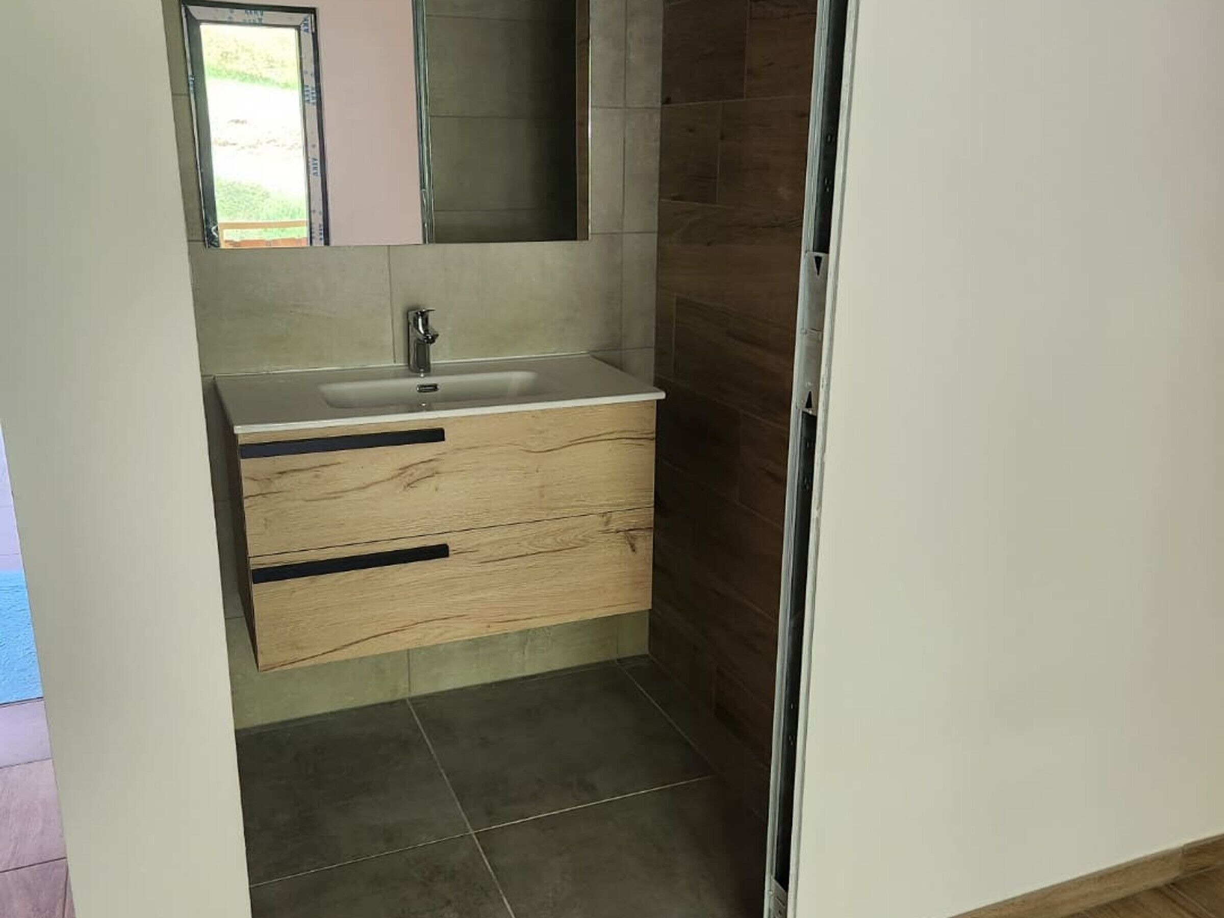 A bathroom with a sink, mirror, and wooden vanity.