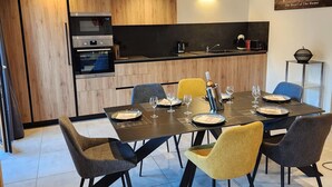 A modern kitchen with wooden cabinetry, a built-in oven, and a dining area with a table set for six. - 3-Room Chalet in Châtel, 6 Pers, South Balcony (Châtel)