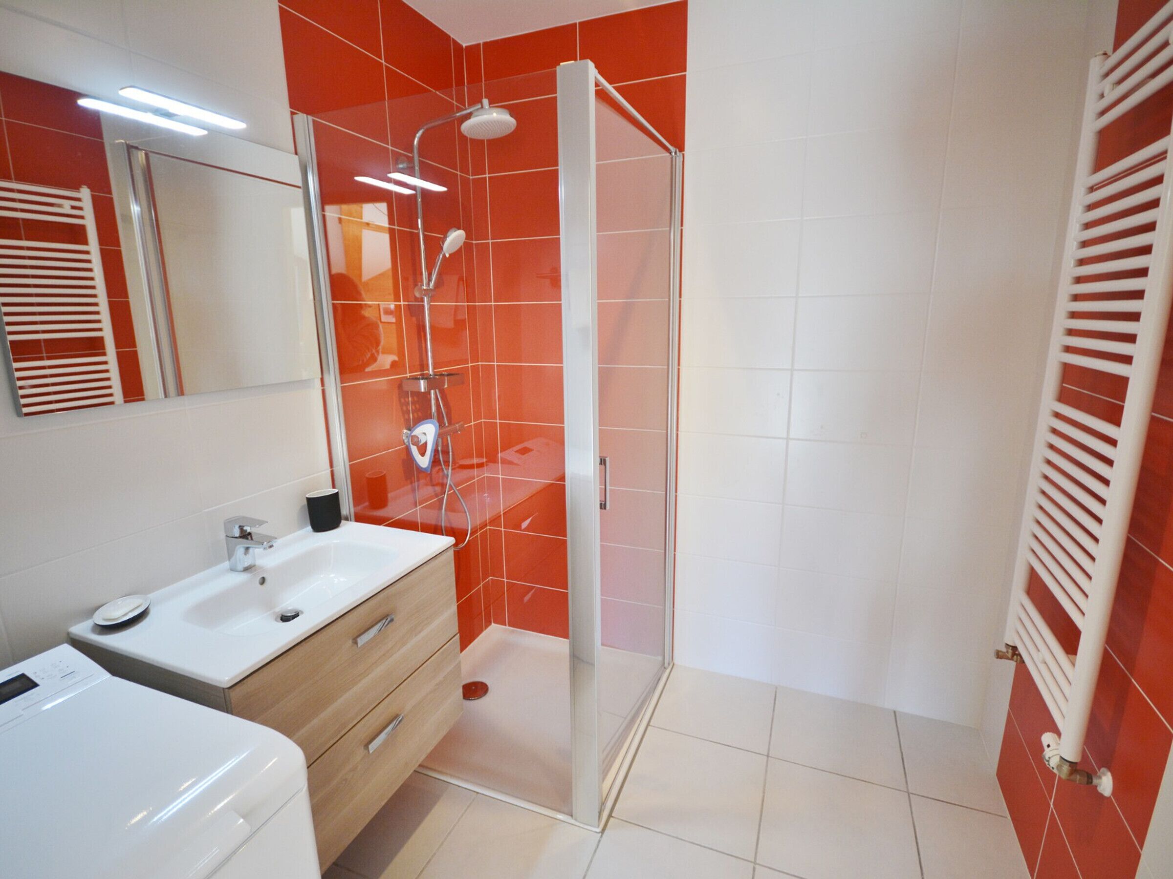 A modern bathroom with a glass-enclosed shower, a vanity with a mirror, and a toilet.