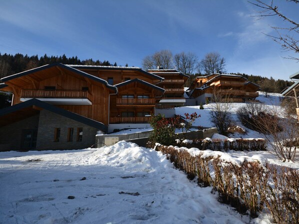 A wooden chalet-style building with multiple balconies and a stone foundation.