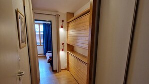 A narrow hallway with wooden flooring and a built-in wooden shelf unit.